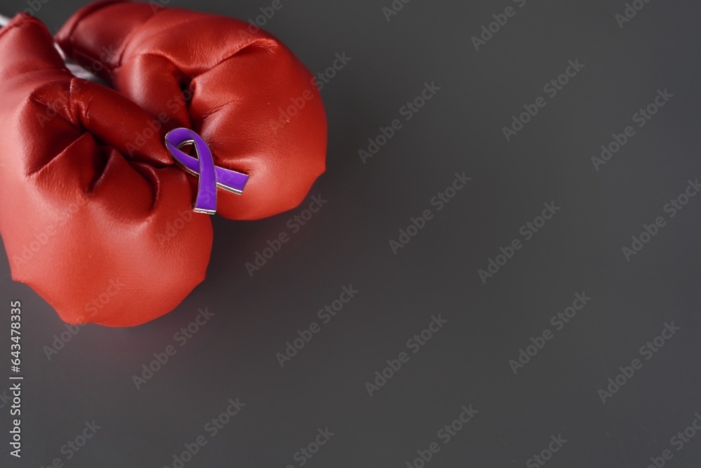 Close up image of boxing gloves and purple ribbon with copy space. Pancreatic cancer, epilepsy and Alzheimer's disease awareness concept