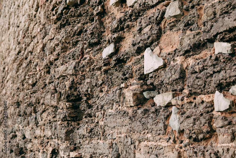 Fototapeta premium An old medieval stone wall, grass and moss on it. Wallpaper, natural background, copy space, soft focus.