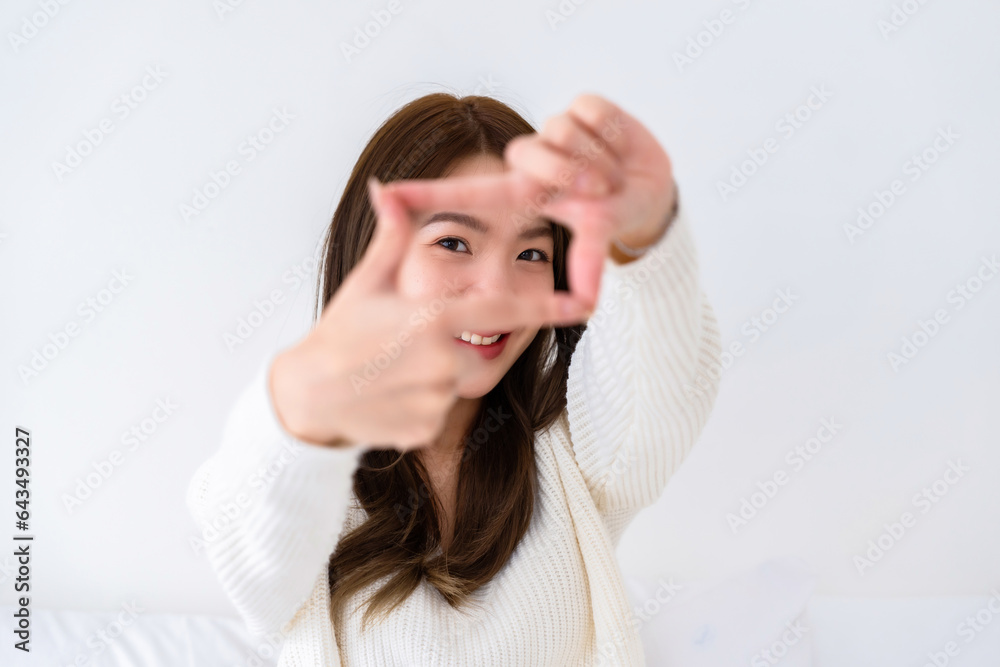 Young asian woman happy and making frame with fingers on white background in house Young asian woman happy and making frame with fingers on white background in house