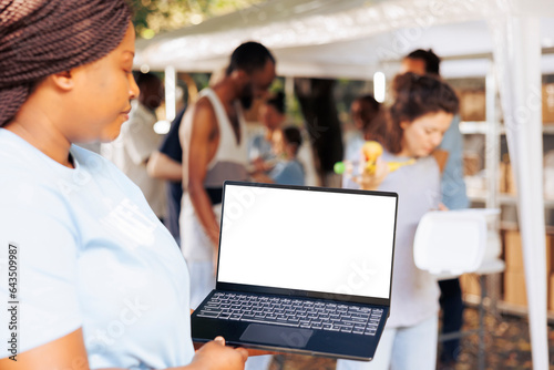 Close-up image showcasing african american female charity worker handling a laptop with blank mockup template. Black woman grasps a minicomputer with isolated copyspace white screen for customization. © DC Studio