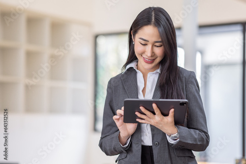 Happy young asian woman, using digital tablet isolated on office background