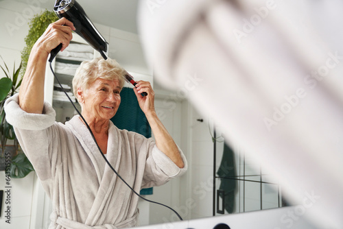 Φωτογραφία Senior caucasian woman drying hair in the bathroom