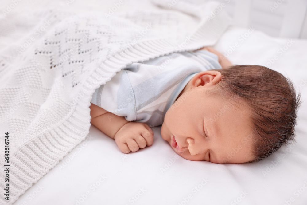 Cute newborn baby sleeping under white plaid in crib Cute newborn baby sleeping under white plaid in crib