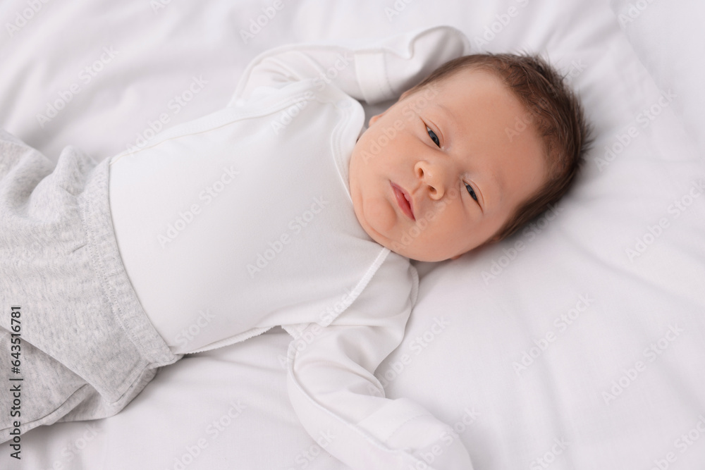 Cute newborn baby lying on white soft bed Cute newborn baby lying on white soft bed