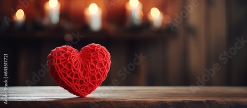 Valentine s Day love concept with a handmade red yarn heart on a wooden table in front of a fireplace