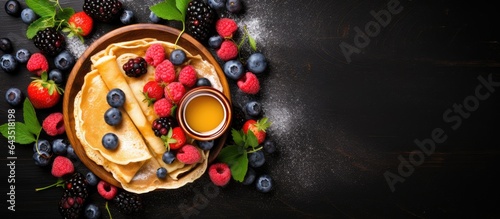 Fruity pancakes with honey on a dark background