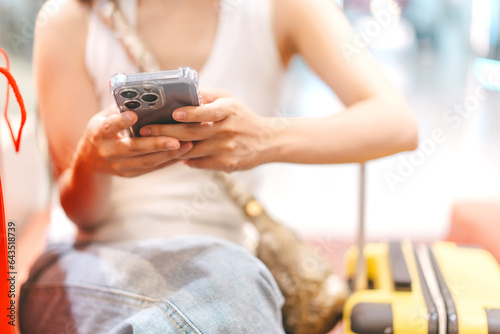 Woman hand using smartphone sitting with travel luggage indoors shopping department store