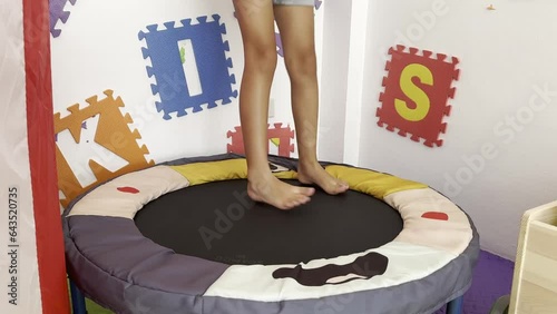 Little girl jumps on children's trampoline in Gymboree. Only girl's legs are visible. Funny holiday and new childhood experiences.