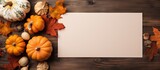 Fall themed flat lay with empty paper and dried leaves alongside a pumpkin on a table Copy space