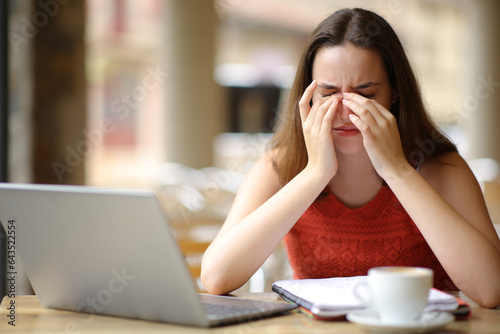 Student suffering eyestrain in a bar terrace