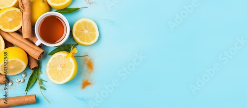 Flat lay with copy space for hot spicy ginger tea in a white cup with lemon honey and spices on a blue background