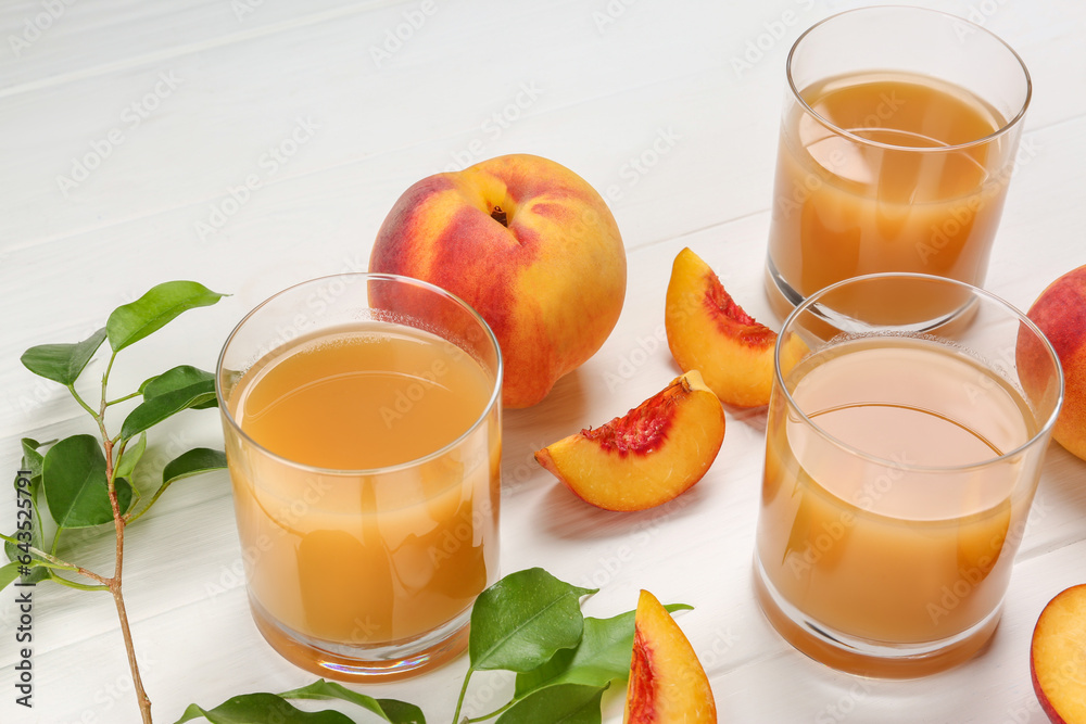 Glasses of peach juice, fresh fruits and leaves on white wooden table Glasses of peach juice, fresh fruits and leaves on white wooden table