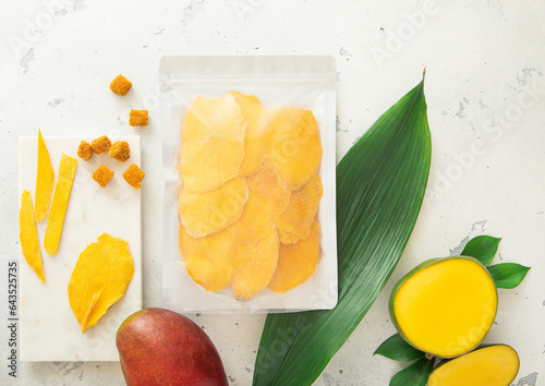 Pack of dried sweet mangoes with leaf and marble cutting board.