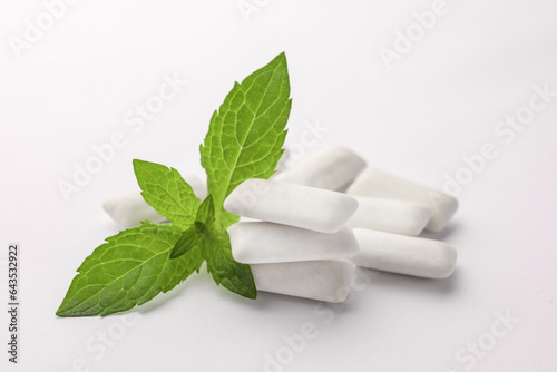 Tasty chewing gums and mint leaves on white background, closeup