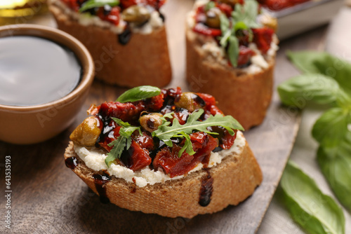 Delicious bruschettas with balsamic vinegar and toppings on table, closeup