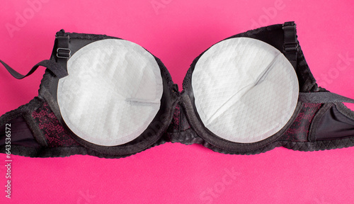 Black bra with liners for the female breast against the flow of milk on a pink background. Womens breast pads, lactation photo