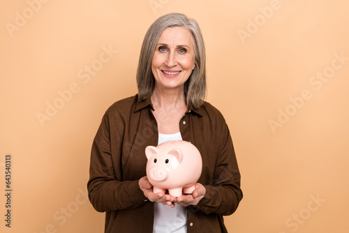 Fotografía Photo of aged cheerful person toothy smile arms hold money savings bank pig isol