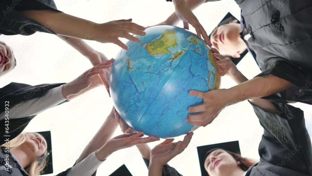 Graduating students twirl a geographic globe of the world in their hands. Graduating students twirl a geographic globe of the world in their hands.