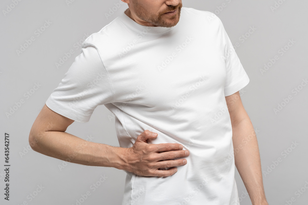 Man touching sick side feeling sharp pain under ribs isolated