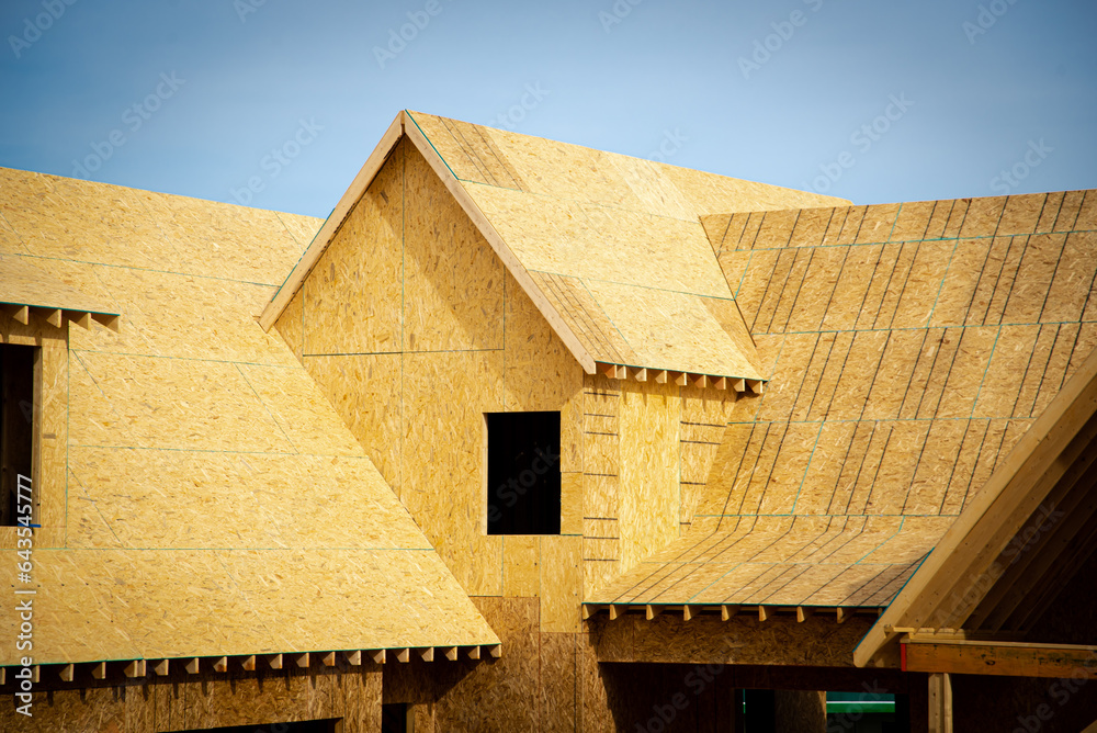 L shaped wooden house with gabled dormer roof under construction