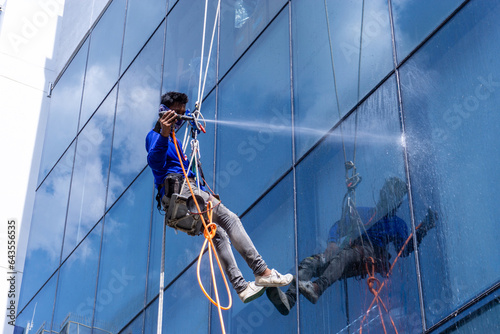 Woker testing water leak on glass facade of highlight building