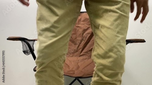 Unidentified man sitting on camping fordable chair brown colour hands fingers flicking and tapping inside room. Thinking and anxious concept