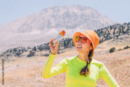 Obraz na płótnie Pretty young woman biting on a energy sportive gel drink after a good hike in high mountains w salonie