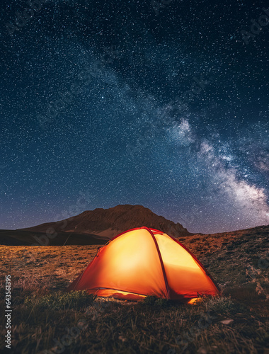 Amidst the mountains, a tent awaits under the starry night, offering a gateway to the universe's mysteries.