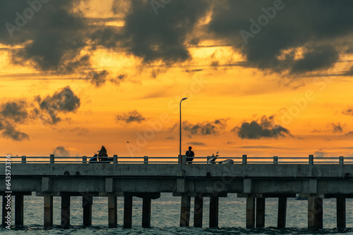 Trat, Thailand - July, 17, 2023 :Pier Bridge Extending into the Sea, Embracing Thailand's Eastern Island's Rocky Shores as sunset time. photo