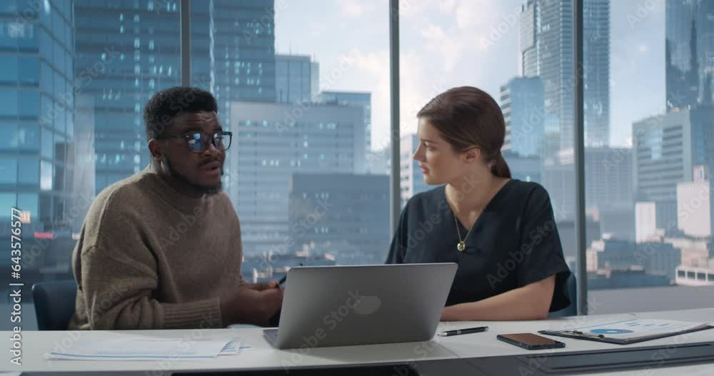 In Diverse Modern Office: Business Meeting of Black Businessman and Caucasian Businesswoman. Businesspeople Working on International e-Commerce Project. Planning and Solving Problems. In Diverse Modern Office: Business Meeting of Black Businessman and Caucasian Businesswoman. Businesspeople Working on International e-Commerce Project. Planning and Solving Problems.