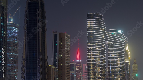 Many towers and skyscrapers with traffic on streets in Dubai Downtown and financial district night timelapse.
