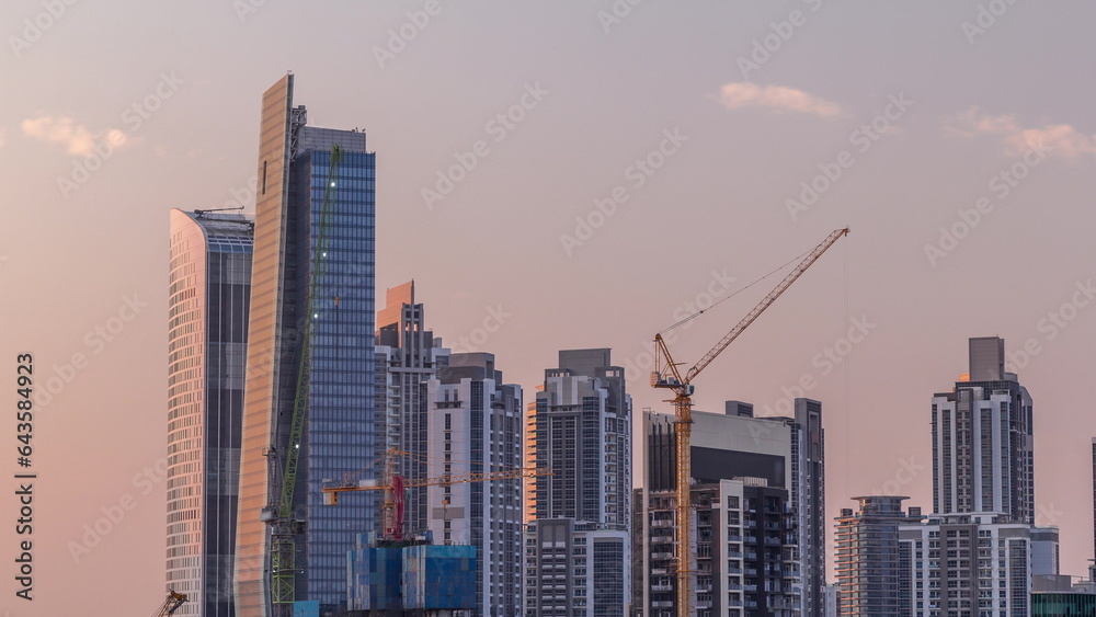 Cityscape with skyscrapers of Dubai Business Bay and water canal aerial timelapse during sunset.