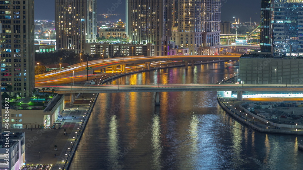 Obraz premium Walking promenade along water canal in Business Bay district of Dubai aerial night timelapse.