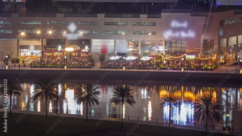 Obraz premium Walking promenade along water canal in Business Bay district of Dubai aerial night timelapse.