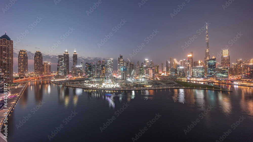 Aerial panorama of Dubai Business Bay and Downtown with the various skyscrapers and towers day to night timelapse