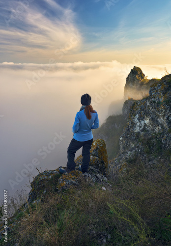 woman stands on a rock above a river canyon. female tourist enjoys foggy autumn landscape. nature of Ukraine