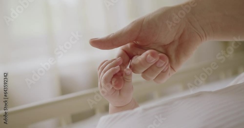 Closeup on baby cute tiny hand gripping mother finger. Cropped view on mom tenderly touching and hold newborn hand. Maternity concept