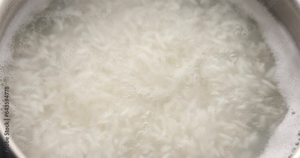 Cooking rice. Close-up of boiling water with rice. Food preparation. A ...