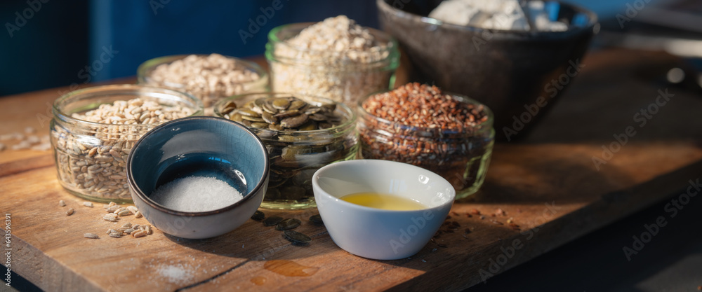 Cereals grains and pumpkin seeds portioned in glasses on rustic wooden board for a bread preparation. Healthy groceries background. - obrazy, fototapety, plakaty 