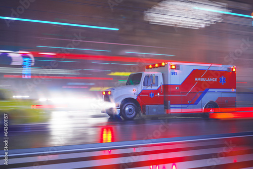 An emergency ambulance on the signal goes through a city streets during night.