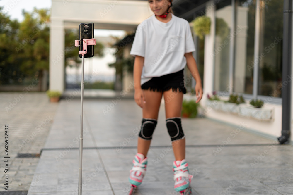 Young girl riding on roller skates at outdoor, child playing on roller skates and recording video for her blog.