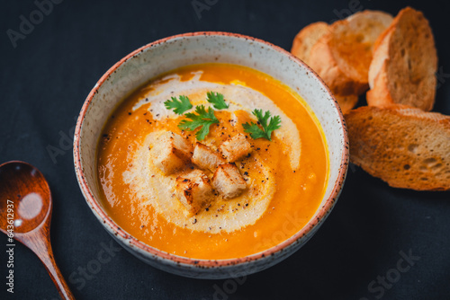 Pumpkin soup with cream on black background