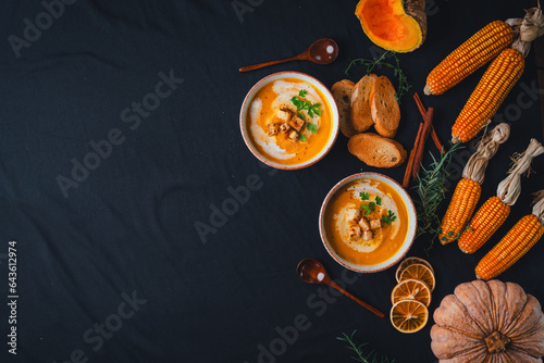 Pumpkin soup with cream on black background