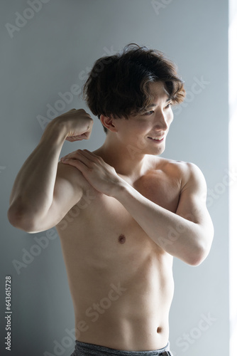 Bild auf Leinwand 筋肉を鍛えるカッコイイハンサムな日本人男性　上腕二頭筋　美しい逆光のイメージの縦