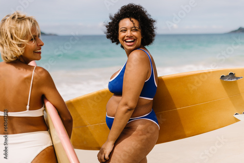 Two women in bikinis going for a surf at the beach