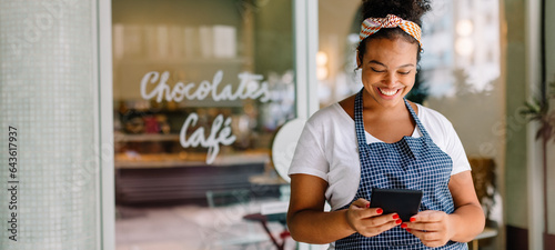 Canvastavla Happy female entrepreneur smiling with digital tablet and smartphone in her cafe
