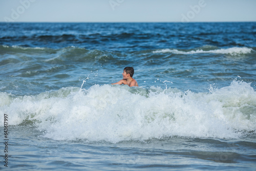 Cheerful teenage boy with a swimming board. Happy european family having fun floating on a swim board in the ocean on a hot summer day