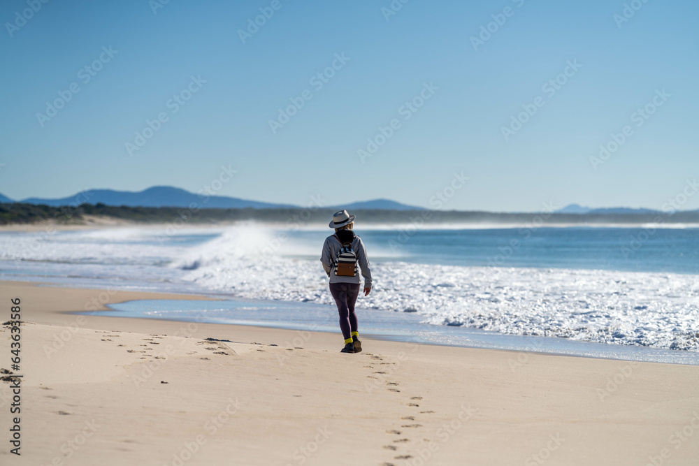 walking on Sandy beach, next to the sea with waves breaking behind, and mountains in the distance walking on Sandy beach, next to the sea with waves breaking behind, and mountains in the distance