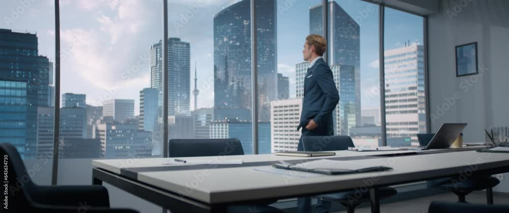 Caucasian Business Manager Entering His Corner Office With Big City View. Male Digital Entrepreneur Standing And Looking Out Of Window Thoughtfully, Planning Business Decisions. Anamorphic Shot
