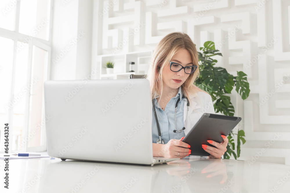 Young attractive female doctor sitting at the desktop in the office and consulting her patient online Young attractive female doctor sitting at the desktop in the office and consulting her patient online